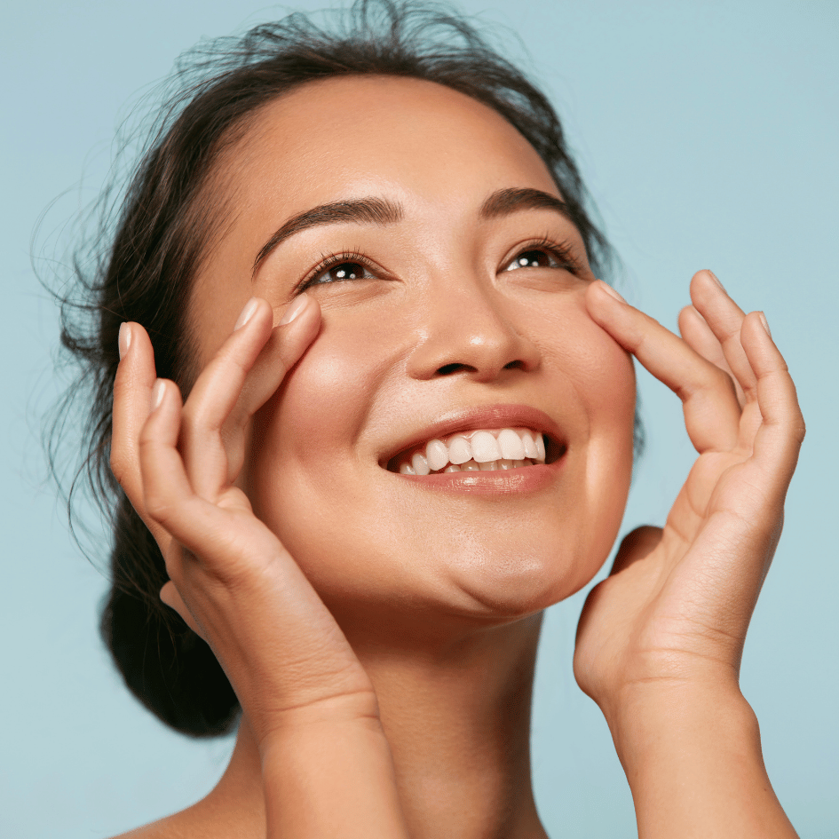 Woman smiling while touching her face, representing the skin health benefits of Peony (Paeonia lactiflora) from Zaira Natural.