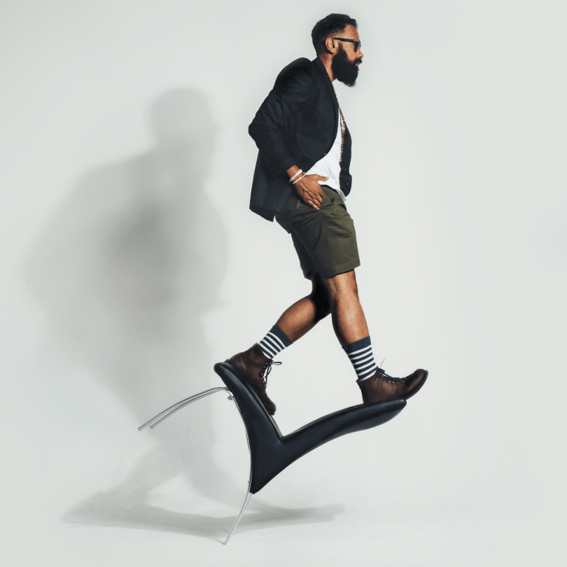 Stylish man balancing on a tilted chair, representing the hormone-balancing benefits of Tribulus fruit on Zaira Natural.
