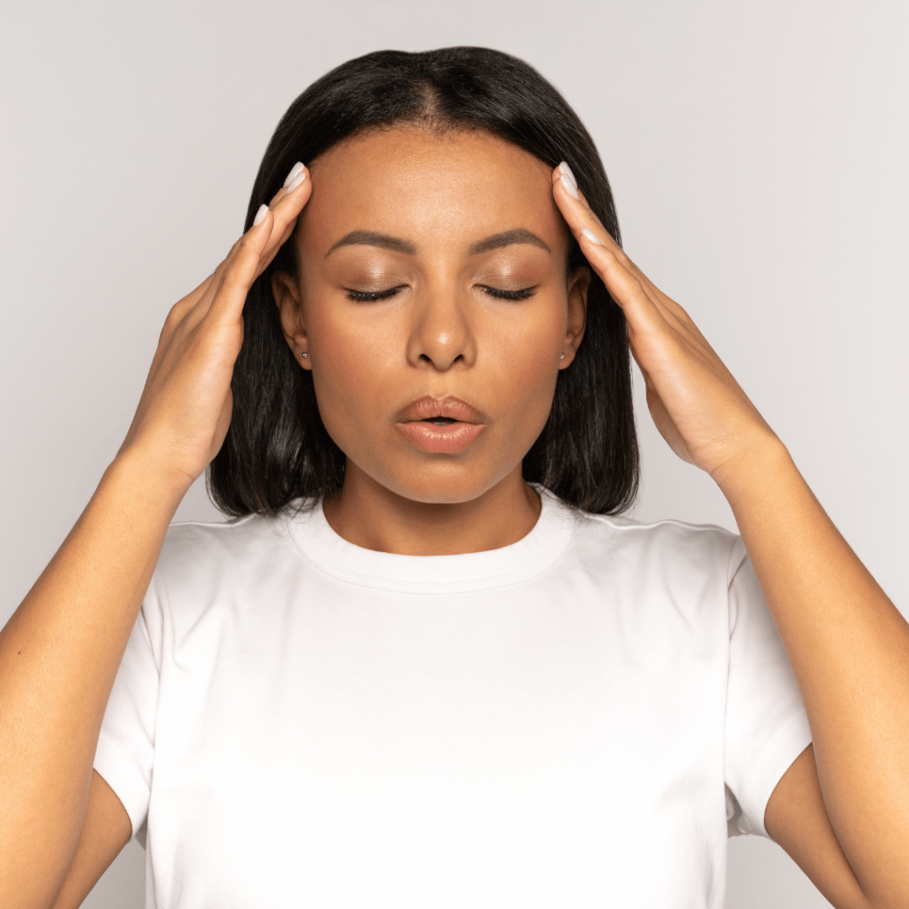 A woman gently massaging her temples to reduce anxiety and stress, representing the calming effects of Gotu Kola.