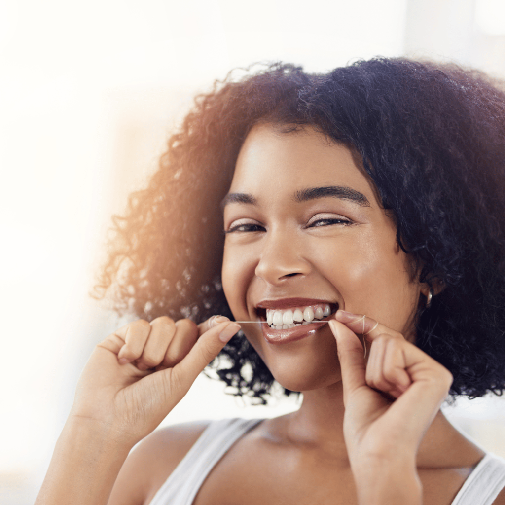 Smiling woman flossing her teeth, symbolizing the oral health benefits of sage.