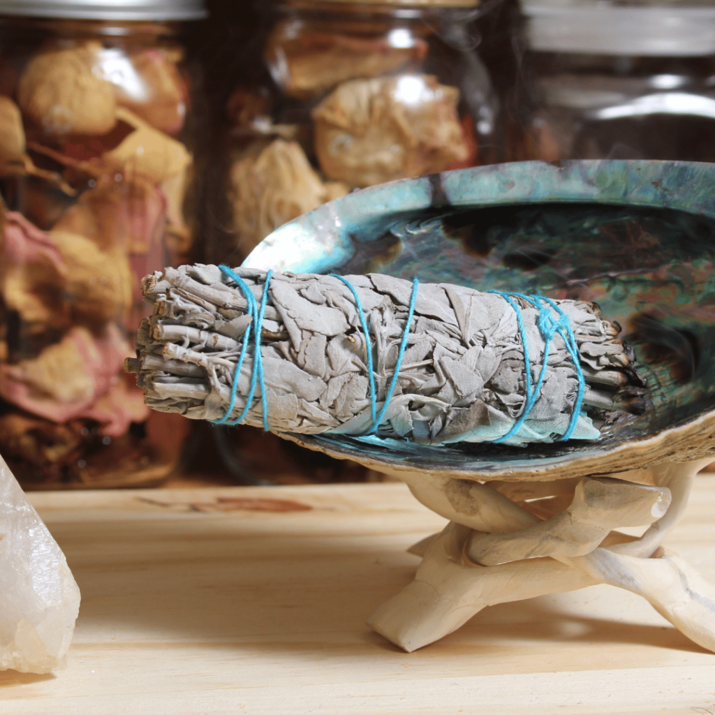 Bundle of dried sage wrapped in twine on a shell, prepared for smudging and aromatic cleansing rituals.