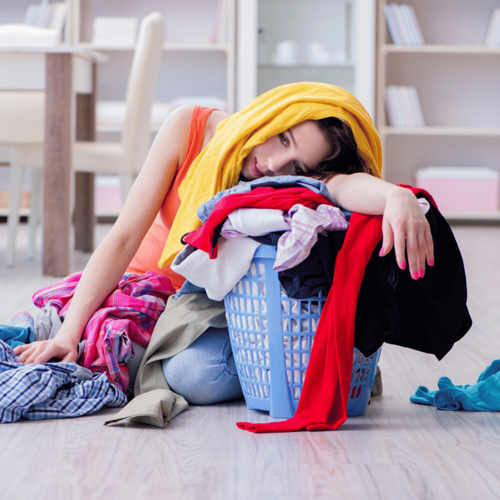 Exhausted woman leaning on a pile of laundry, symbolizing stress and the potential mood-enhancing benefits of sage.