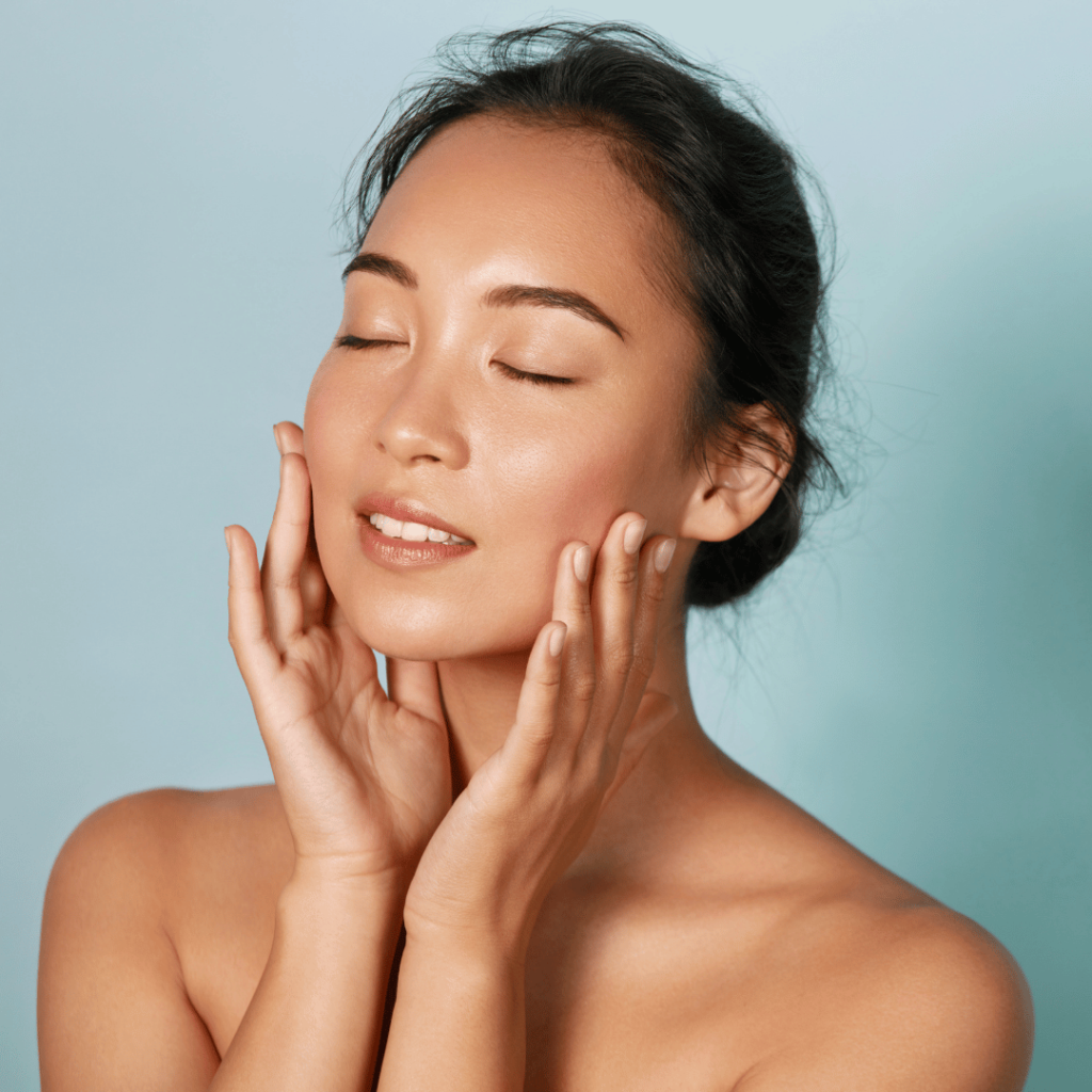 A woman gently touching her face, representing the skin health benefits of Moringa by Zaira Natural.